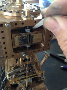 a person is working on a machine with wood and metal parts in the foreground