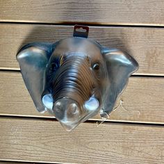 an elephant mask hanging from the side of a wooden wall