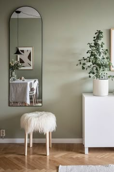 a white bench sitting next to a mirror on a wall near a table with a potted plant