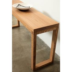 a wooden table with a bowl on top of it and another plate sitting on the edge