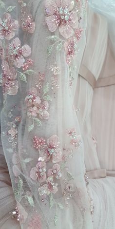 a white dress with pink flowers on it and sequins around the neckline