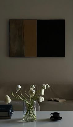 a vase filled with white flowers sitting on top of a table next to a book