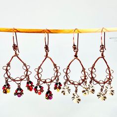 five pairs of earrings hanging from a wooden hanger on a clothes line with strings