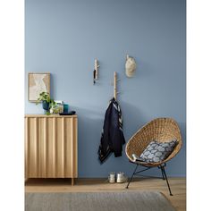 a room with blue walls and a rattan chair next to a coat rack on the wall