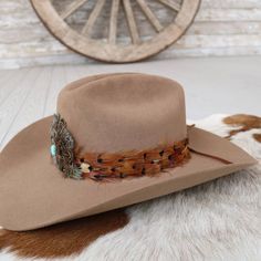 The Stellar Western Feather Hat Band, measuring 3 cm in width and approximately 58 cm in length (excluding the leather ties), offers a refined touch to any hat. Designed to fit most, it features adjustable leather ties for a secure and comfortable fit. The center crown, measuring 2.5" W x 2.25" H, adds a distinctive element, while the feather detailing brings a touch of rustic charm, making this hat band a stellar addition to any western-inspired wardrobe. Brown Hat Bands With Feathers For Western-themed Events, Adjustable Wide Brim Top Hat For Ranch, Classic Adjustable Fur Felt Hat Bands, Western Style Brown Hat With Flat Crown, Western Style Brown Fedora With Flat Crown, Western Brown Fedora With Flat Crown, Adjustable Fur Felt Hat For Kentucky Derby, Classic Adjustable Brown Felt Hat, Brown Fur Felt Hat Bands For Western-themed Events