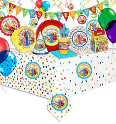 a birthday party set up with balloons, streamers and confetti on the table