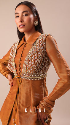 Experience the splendor of our copper brown kurta and palazzo set.
The jacket is detailed with cutdana and sequins.
This set is made from crepe tussar fabric.
This outfit is ideal for mehendi and sangeet events.
The kurta is coupled with a jacket and dhoti. Traditional Gold Embroidered Kurta With Drape, Designer Kurti, Brown Embroidered Traditional Drape Wear, Brown Kurta With Resham Embroidery In Traditional Drape, Indo Western Outfits, Dhoti With Shrug, Dhoti With Jacket, New Dress Design Indian, Dotti Dresses