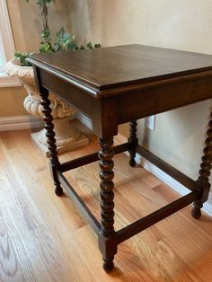 a wooden table sitting on top of a hard wood floor next to a potted plant