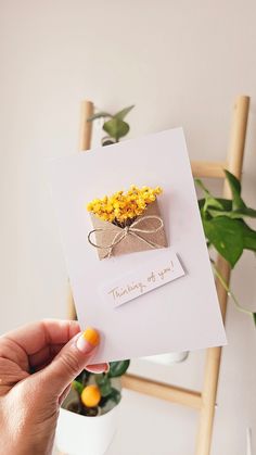 a person holding up a card with flowers on it and the words thinking of you