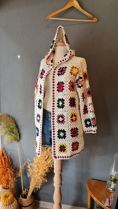 a crocheted jacket is hanging on a coat hanger next to other items