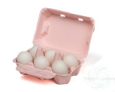 an egg carton filled with six eggs on a white surface, one in the middle