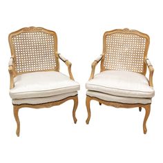 a pair of chairs with cane back and white upholstered seat, both side by side