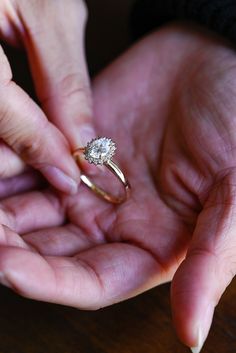 two people holding out their hands with a diamond ring on it's finger,