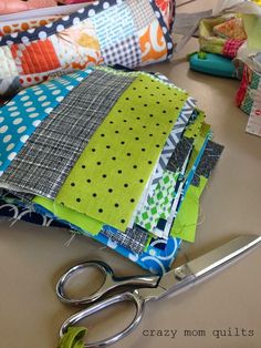 a pair of scissors sitting on top of a table next to quilts and fabric