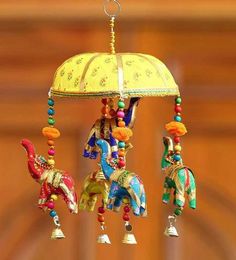 three colorful elephants hanging from a chandelier with a yellow shade over it's head