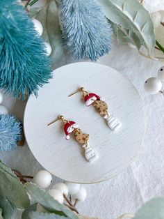 the small earrings are decorated with santa clause's hat and snowman on them