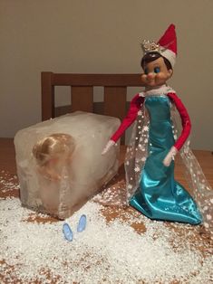 there is a doll next to an ice block on the table with snow all over it