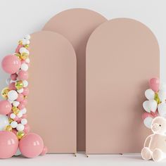 a teddy bear sitting next to balloons and a pink arch that says love on it