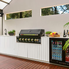 an outdoor kitchen with coolers and drinks on the outside wall, along with wood flooring