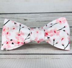 "Pale pink cherry blossoms on white cotton sateen. Because of the handmade nature of these bowties they can vary in size ever so slightly but on average the bow measures 5 inches by 2 inches when tied. hand wash/ spot wash only The self-tied option will be made in the style pictured. The pre-tied option will have the addition of a hook in the back, and the bow will be stitched in the tied position. RETURNS: I accept returns on items in original, unused condition. You will receive a refund for th White Summer Bow For Gifts, Pink Bow Gift For Spring, White Bow Tie For Gifts, White Bow Tie Gift, Elegant Adjustable Bow Tie For Spring, Decorative Bow For Spring Gifts, Adjustable Elegant Spring Bow Tie, Spring Formal Bow Tie With Decorative Bow, Pink Butterfly Knot Bow For Summer