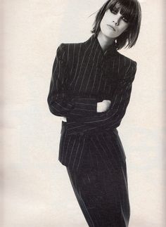 a black and white photo of a woman in a suit with her arms folded out