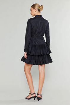 Get ready for a statement piece with this all-black, high-neck shirt dress. Carefully crafted pleats add texture and structure, highlighting the neckline and placket, as well as the skirt's tiers. Elegant Pleated Tiered Skirt Dress, Elegant Pleated Tiered Dress, Fitted Dress With Pleated Waist And Tiered Skirt, Chic Pleated Tiered Skirt Dress, Fitted Pleated Tiered Mini Dress, Party Dress With Pleated Waist And Tiered Skirt, Tiered Skirt Dress With Pleated Waist For Party, Fitted Tiered Dress With Pleated Skirt, Elegant Ruffled Shirt Dress For Daywear