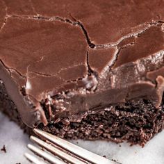 a piece of chocolate cake sitting on top of a white plate next to a fork