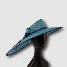 Asymmetric wide brim hat made from azure blue sinamey, trimmed with dark blue ribbon and decorated with elegant bow. The wide brim make it really special and suits almost all face types. The hat is hand blocked on a wooden block and hand stitched to perfection at Irina Sardareva millinery atelier. It is great to wear on Derby races, Royal Ascot ,Cocktail parties, Weddings, Tea parties, etc. The brim on the right side is 8 inches, on the left side - 5 inches The size is universal, there is a millinery elastic that keeps the hat stable on your head. This hat is on stock and can be sent in 1-2 working days. This hat will be shipped with postal service and will be delivered to USA and Canada in 3 weeks, UK - 2 weeks, EU - 1 week Blue Boater Hat With Curved Brim For Beach, Chic Blue Straw Hat For The Beach, Blue Chic Straw Hat For Summer, Chic Blue Straw Hat For Summer, Chic Blue Beach Hat, Formal Top Hat With Curved Brim For Royal Ascot, Formal Blue Fedora Hat, Blue Straw Hat For Summer Parties, Elegant Blue Fedora With Short Brim