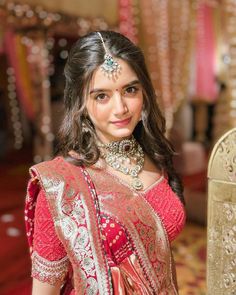 a woman in a red and gold sari posing for the camera with her hand on her hip