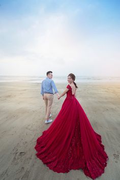 a man and woman holding hands on the beach