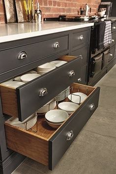 an open drawer in the middle of a kitchen counter with plates and bowls on it