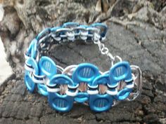 a blue and white bracelet on a tree branch with chains attached to the clasps