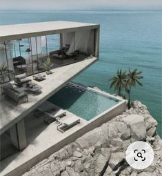 an oceanfront house with a pool and lounge chairs on the cliff overlooking the water