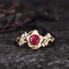 a close up view of a ring with a red stone in the center on a rock