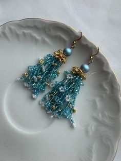 Discover the beauty of these handcrafted blue and gold seed bead earrings, accentuated with a sparkling zircon stone. Expertly made with attention to detail, these earrings offer a blend of elegance and charm, ideal for any occasion. The intricate design showcases vibrant colors that enhance their appeal, ensuring they complement both casual and formal attire with grace. Each pair is crafted uniquely, guaranteeing both quality and individuality. Treat yourself or a loved one to these exquisite earrings, perfect for adding a touch of sophistication to any outfit. Comes in a Cardboard box, ready to be a perfect gift for you or someone you want to make happy. P.S.   box, not the same as on the picture. Elegant Blue Chandelier Earrings For Celebration, Blue Dangling Beads Earrings For Celebration, Blue Festive Chandelier Drop Earrings, Blue Dangling Beads Earrings For Festive Occasions, Blue Beaded Earrings With Colorful Beads As Gift, Festive Blue Earrings With Dangling Beads, Light Blue Jewelry With Colorful Beads For Party, Elegant Turquoise Chandelier Earrings With Round Beads, Elegant Gold Earrings With Colorful Beads