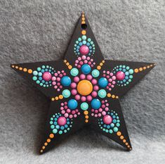 a painted wooden star ornament sitting on top of a gray surface with beads