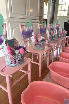 there are many pink tubs with toothbrushes in them on the tables and chairs