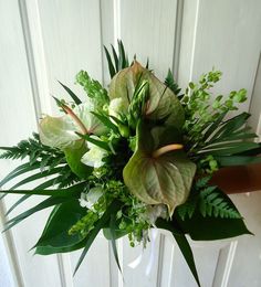 a bouquet of green and white flowers in front of a door