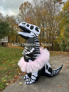 a person in a costume that is sitting on the ground near some grass and trees