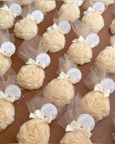 some white cupcakes with bows and tags on them are sitting on a table