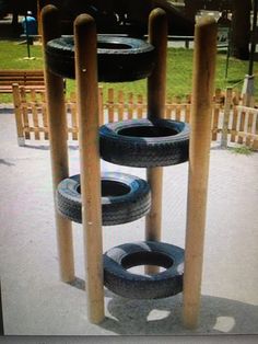 three tires are stacked on top of each other in a playground area with people walking by