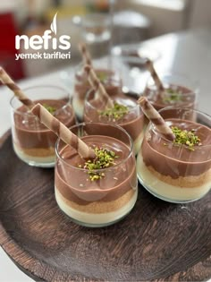 small desserts with chocolate and pistachio toppings on a wooden platter