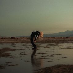 a woman standing on top of a wet beach