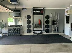 a garage gym with black mats and lots of exercise equipment on the wall behind it