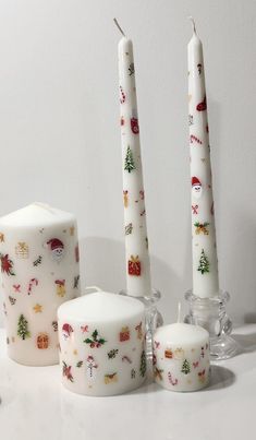 three white candles with christmas decorations on them