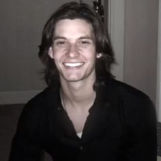 a man smiling and wearing a black shirt