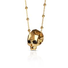 a gold skull necklace with black stones on the front and back end, hanging from a chain