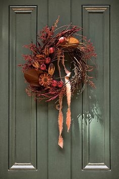 a green door with a wreath hanging on it's side and an orange ribbon tied to the front