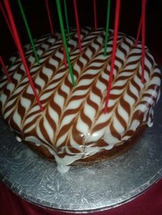 a cake with white and brown icing on a silver platter topped with red and green candles