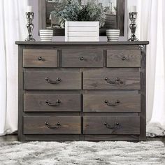 a dresser with many drawers in front of a mirror and white curtains on the window sill